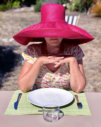 Woman wearing pink hat while sitting at table in restaurant