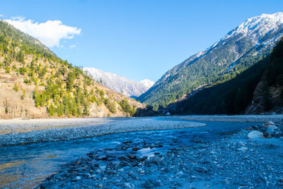 Scenic view of lake by mountains against blue sky