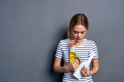 Young woman looking away while standing against wall