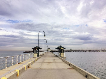 Footpath leading towards st kilda pier kiosk against cloudy sky