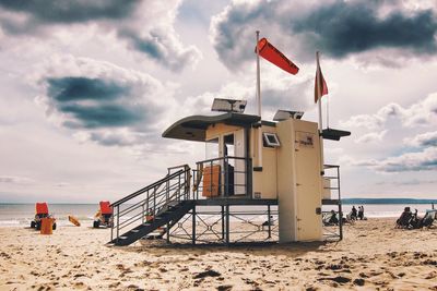 Lifeguard hut on beach against cloudy sky