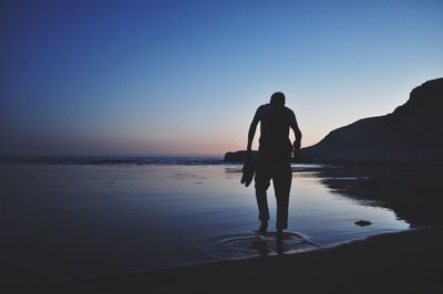 Rear view of silhouette man standing on beach