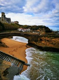 Bridge over river against cloudy sky