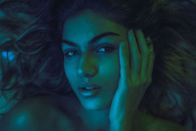 High angle portrait of young woman lying on bed at home