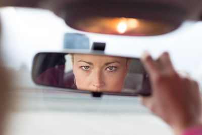 Portrait of woman reflecting in car