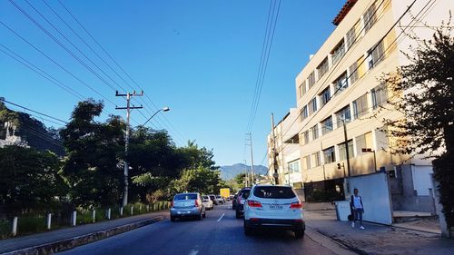 Cars on street in city against clear sky