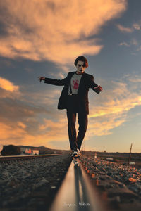 Full length of man standing on shore against sky during sunset