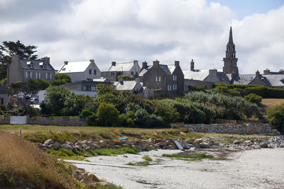 Buildings by river against sky