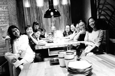 Portrait of happy friends sitting at dining table during social gathering