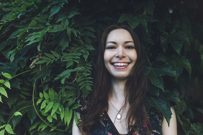 Portrait of cheerful optimistic brunette in a green foliage, smiling. close up.