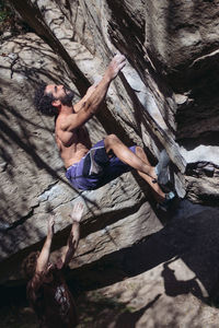 Shirtless man climbing rock