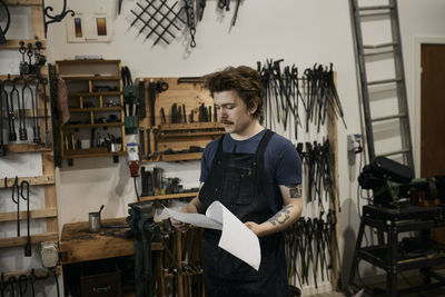 Blacksmith reading documents in his workshop