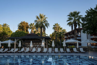 Deck chairs and umbrellas arranged at poolside under clear blue sky at resort