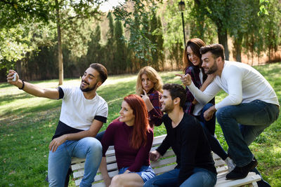 Happy friends taking selfie with smart phone at public park