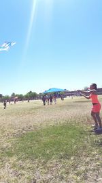 People on grassy field against sky