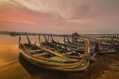 Boat moored in sea against sky during sunset