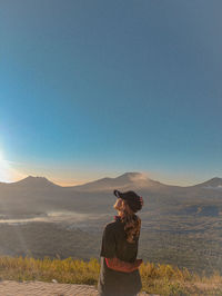 Rear view of woman standing on landscape against clear sky