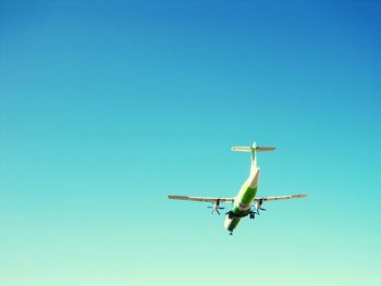 Low angle view of airplane flying against clear blue sky