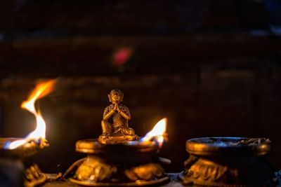 Lit candles in temple against building