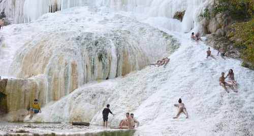 Group of people walking along rocks in water