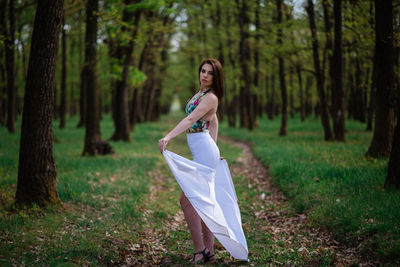 Woman standing on tree trunk in forest