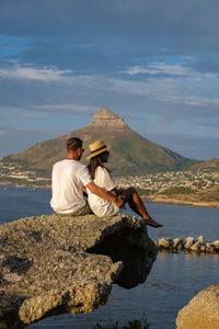 Rear view of couple sitting on cliff