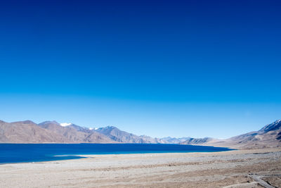 Scenic view of snowcapped mountains against clear blue sky