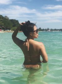 Young woman standing in sea against sky