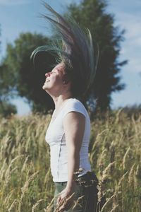 Woman tossing hair while standing on field