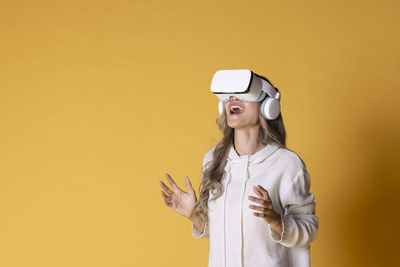 Portrait of woman wearing sunglasses while standing against yellow background