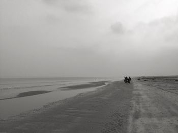 People walking at beach against sky