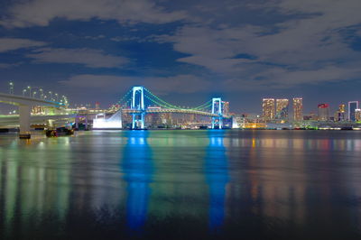 Illuminated bridge over river against sky in city at night