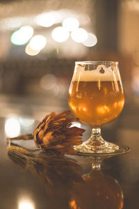 Close-up of beer glass with flower on table in illuminated room