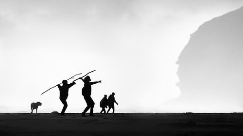 Silhouette people on land against sky