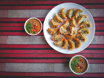 Flat lay of deep-fries gyoza on white plate with dipping sauce and peanut. chinese food.