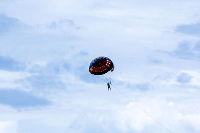 Low angle view of person paragliding against sky