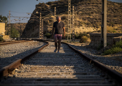 Man walking on railroad track in summer with sunlight and shadow