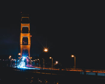 Illuminated light trails on golden gate bridge against sky at night