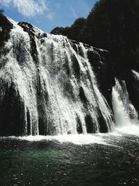 Scenic view of waterfall against sky