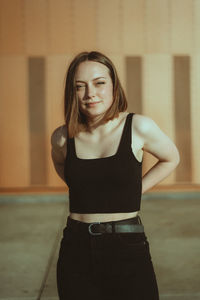 Portrait of young woman standing against wall