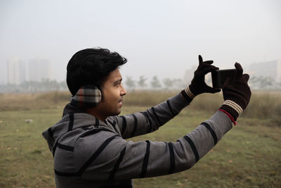 Side view portrait of young man on land against sky