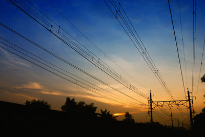 Low angle view of silhouette electricity pylon against sky during sunset