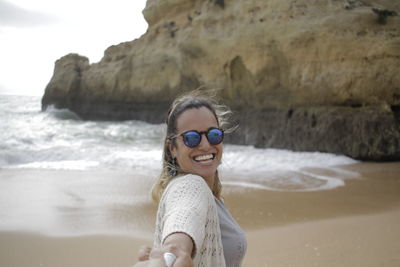 Cropped hand holding happy woman at beach