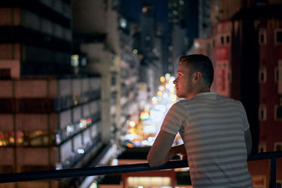 Rear view of man looking at illuminated city at night