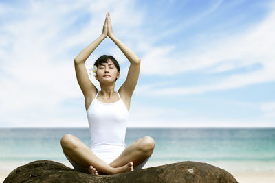 Woman doing yoga against sea and sky