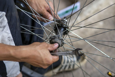 Close-up of man working on bicycle