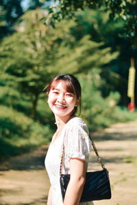 Portrait of young woman standing against trees