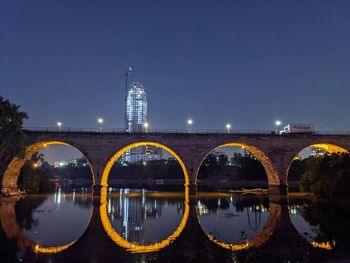 Arch bridge over river in city at night