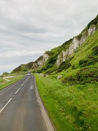 Road leading towards mountains against sky