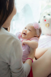 Close-up midsection of woman holding cute newborn baby girl at home